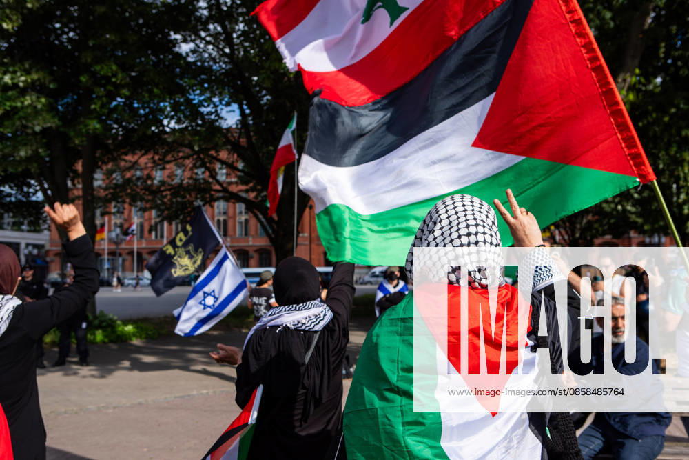 A participant draped in a Palestinian flag raises a peace sign during a Naksa Day demonstration at Neptunbrunnen in Berlin, Germany while in the background Israel supporter can be seen. Berlin Germany - ZUMAc291 20260605_zip_c291_004