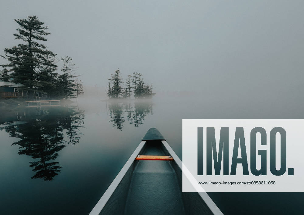 Canoe glides across a still lake in heavy fog in early morning Buck Lake, Ontario, Canada CR_DOHO260604G-2040778-01