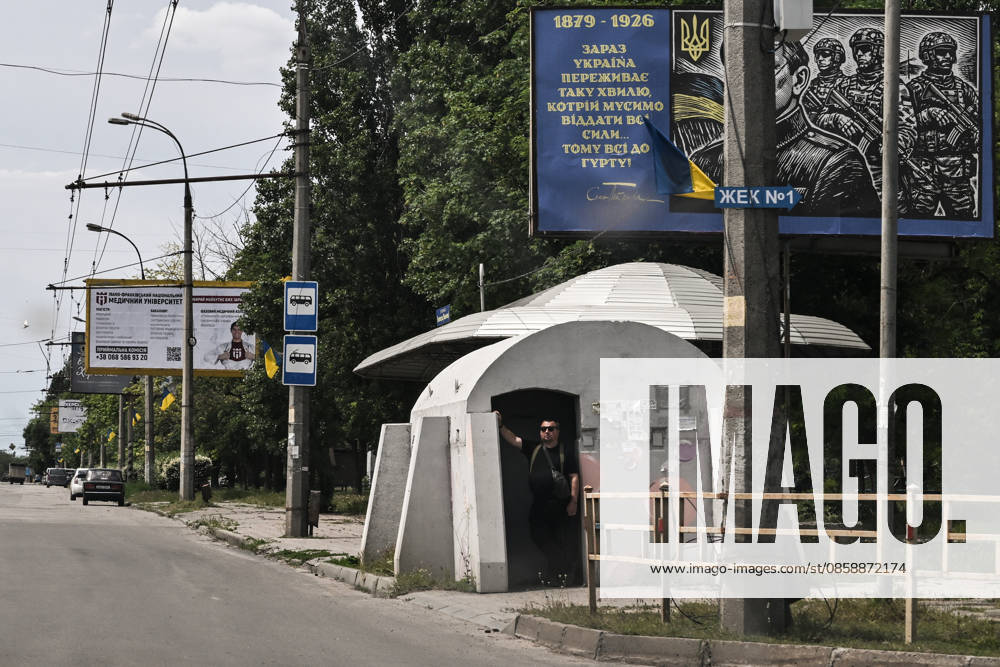 A man stands at the entrance to a mobile concrete shelter installed at a public transport stop in the frontline city of Kherson, Ukraine, on June 2, 2026. The Russian army attacks the city daily with FPV drones and other unmanned aerial vehicles, deliberately terrorizing civilians. Russian forces conduct hunts for local residents, tracking them with FPV drones and _drop_ping explosives. Police officers, medics, public transport, and urban infrastructure are also targeted. Based on the intensity of attacks, Kherson is informally divided into yellow and red zones, with the red zone considered the most dangerous due to constant shelling and drone strikes. Anti-drone netting has been installed above roads to help protect against Russian
