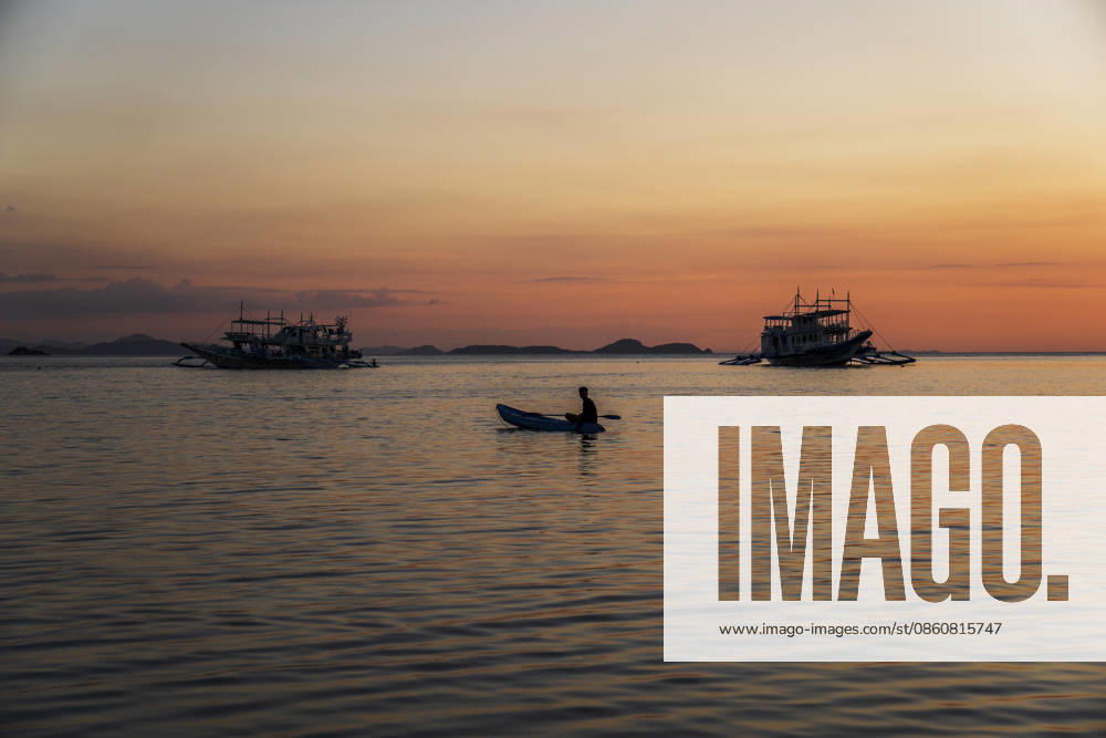 A male paddles a small boat during a tropical sunset in El Nido model released, Symbolfoto, PNAF07101