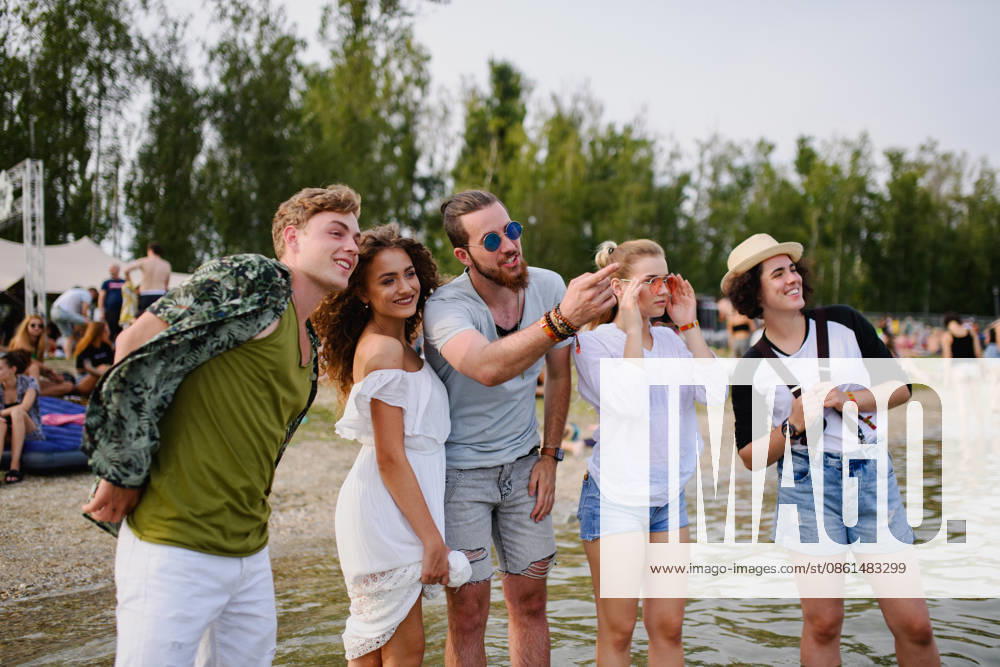 Group of young friends at summer festival. Group of cheerful young friends at summer festival, standing in lake water. model released
