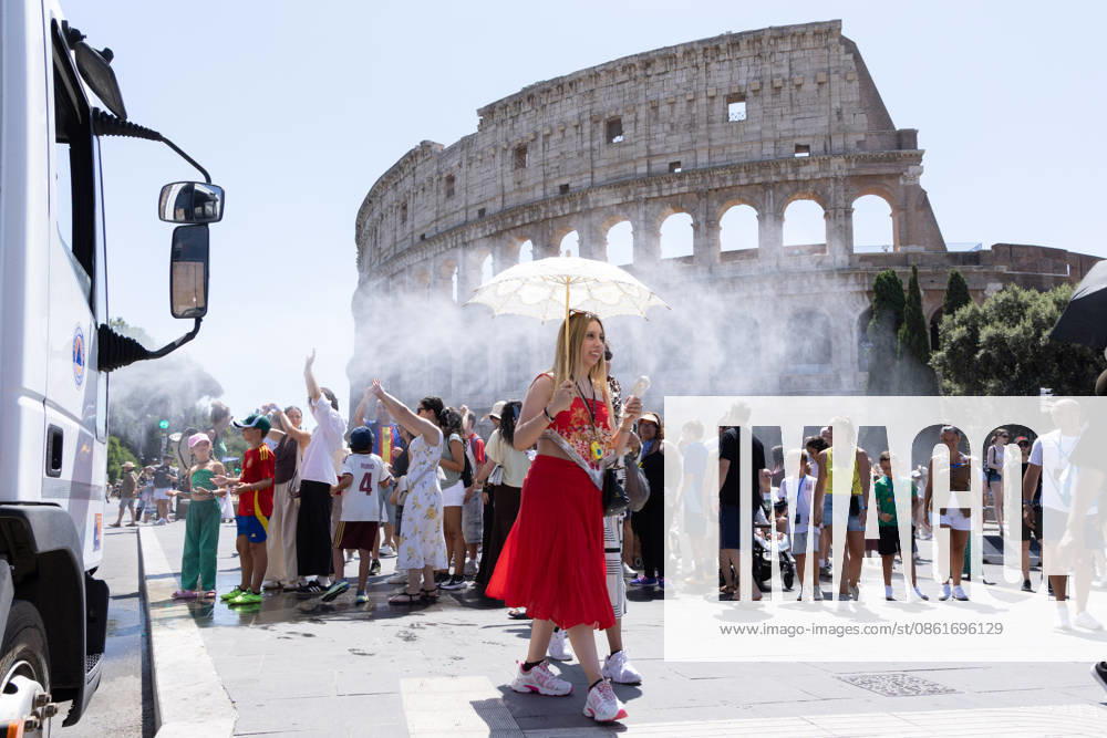 IPA86702498 - Tourists seek relief from the heat under the misting spray in front of the Colosseum in Rome