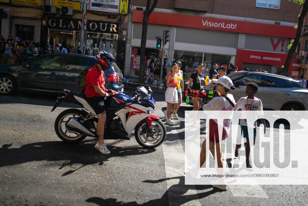 A couple throws water at a motorcyclist.during the Water Battle in the working-class neighborhood of Vallecas, Madrid. This celebration began in 1981 due to the high temperatures, when residents started throwing water at each other. It is also part of the festivities for the Virgen del Carmen, patron saint of sailors. Madrid Spain - ZUMAs197 20260719_aaa_s197_136