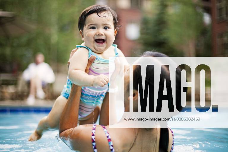 A Japanese American mother swims and holds her 10 month old baby girl in a swimming pool., Breckenridge Colorado USA model released Symbolfoto