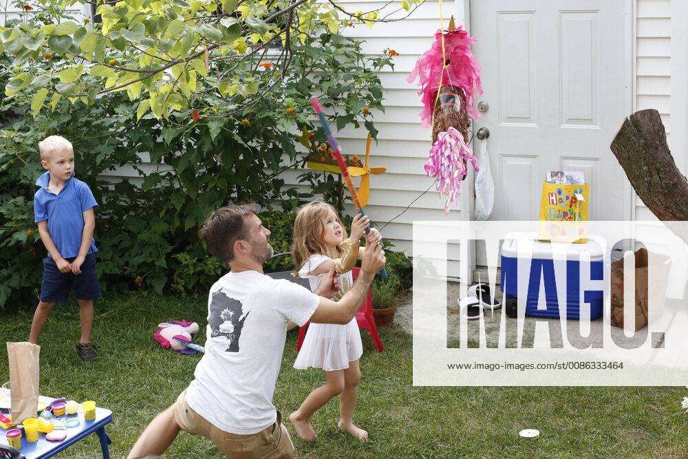 Mid adult father playing with little daughter during birthday party in front or back yard, Oak Park IL United States model released Symbolfoto