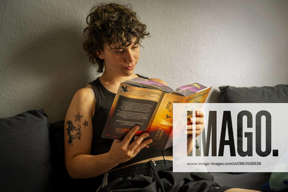 Buchreihe von Rebecca Yarros, IRON FLAME, ein Teenager in Bad Wörishofen in Bayern sitzt auf ihrem Sofa und liest ihr Spannendes Buch. (Modelreleased) 07.08.2026, Jugendbücher 07.08.2026, Jugendbücher