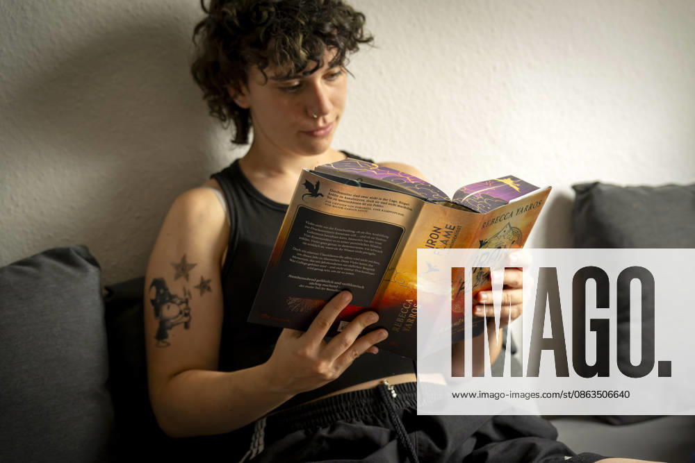 Buchreihe von Rebecca Yarros, IRON FLAME, ein Teenager in Bad Wörishofen in Bayern sitzt auf ihrem Sofa und liest ihr Spannendes Buch. (Modelreleased) 07.08.2026, Jugendbücher 07.08.2026, Jugendbücher