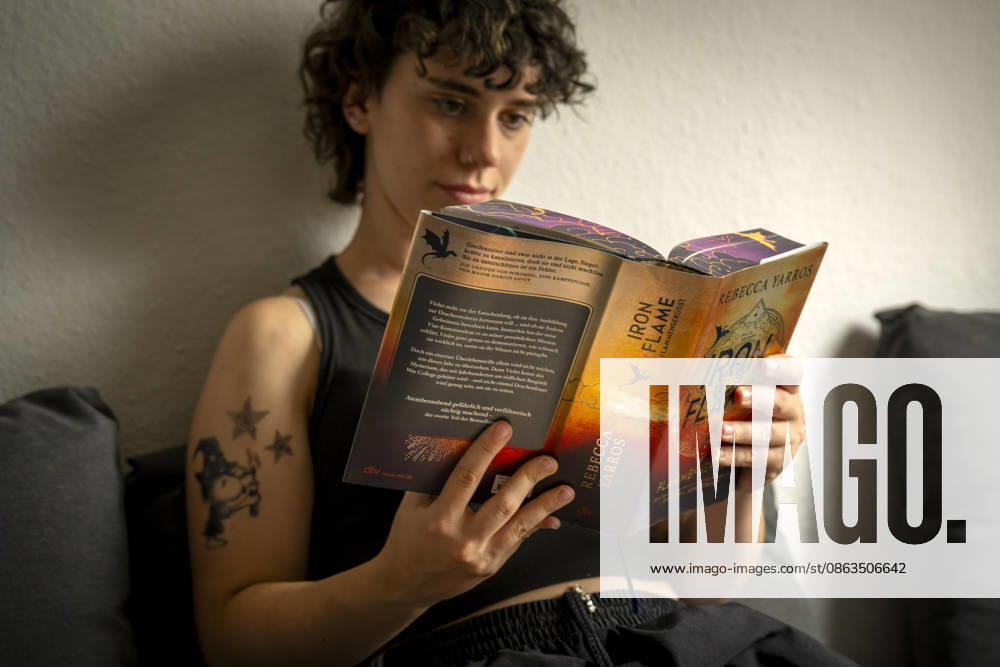 Buchreihe von Rebecca Yarros, IRON FLAME, ein Teenager in Bad Wörishofen in Bayern sitzt auf ihrem Sofa und liest ihr Spannendes Buch. (Modelreleased) 07.08.2026, Jugendbücher 07.08.2026, Jugendbücher