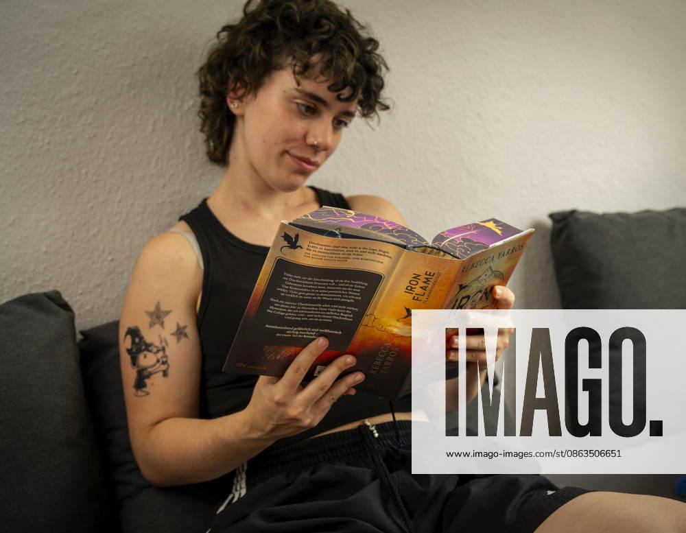 Buchreihe von Rebecca Yarros, IRON FLAME, ein Teenager in Bad Wörishofen in Bayern sitzt auf ihrem Sofa und liest ihr Spannendes Buch. (Modelreleased) 07.08.2026, Jugendbücher 07.08.2026, Jugendbücher