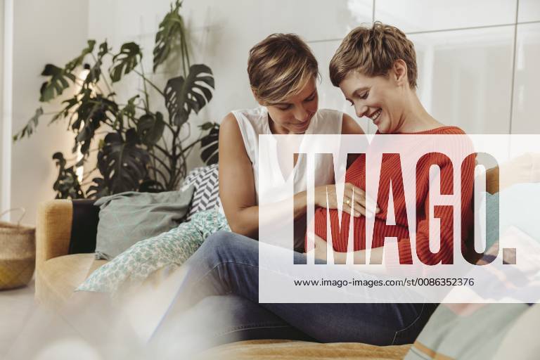 Happy lesbian couple touching belly of the expectant mother model released Symbolfoto property released MFF04442