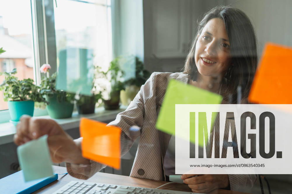 Smiling businesswoman planning strategy with notes at home office model released, Symbolfoto property released, ANAF06471