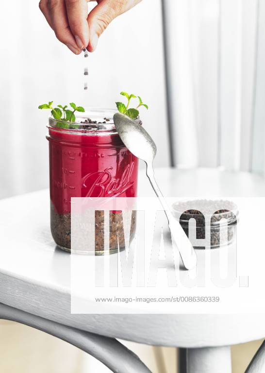 Woman s hands sprinkling glass of rhubarb and chia seeds dessert with dark chocolate nibs model released Symbolfoto RAMAF00104