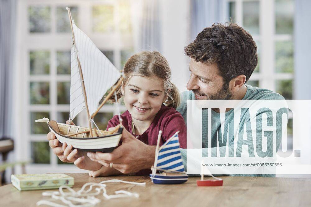 Happy father and daughter playing with model boat at home model released Symbolfoto property released RORF01396