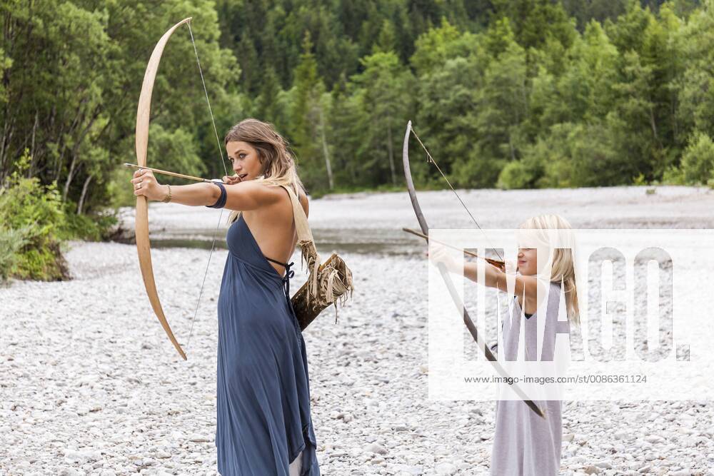 Mother and daughter aiming with bow and arrow in the nature model released Symbolfoto TCF05787