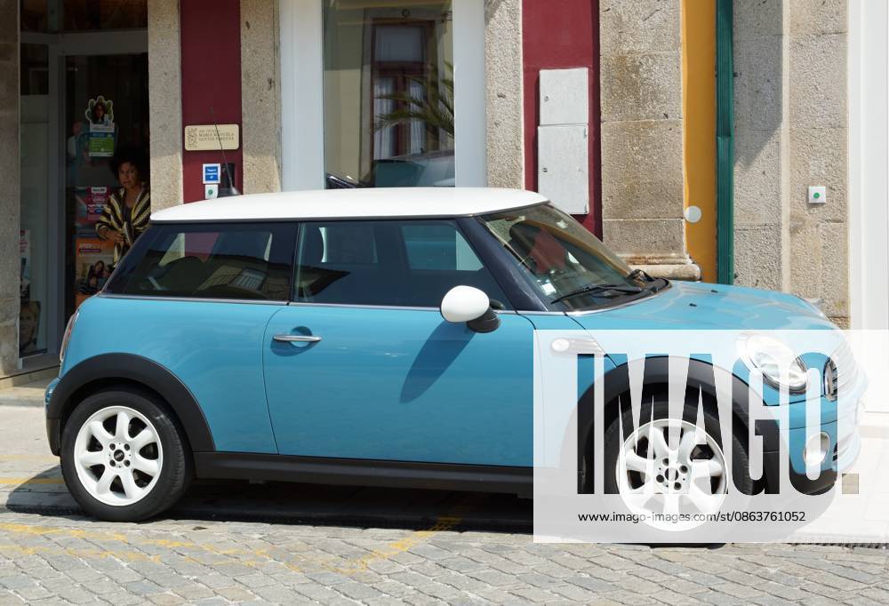 Ein blauer Mini Cooper, der auf einer Stadtstraße geparkt ist Blue Mini Cooper showcasing urban driving and transportation on a cobblestone street (License=RM)