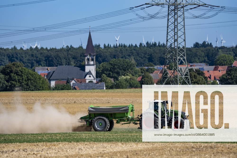 Trecker mit Mineraldüngerstreuer, bearbeitet ein abgeerntetes Getreidefeld, streut mineralischen Dünger, Kalk aus, um die Qualität des Boden für eine erneute Nutzung, Aussaat zu steigern, bei Marsberg-Meerhof, NRW, Deutschland Feldarbeit