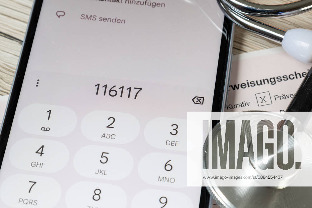 Symbolbild: Nahaufnahme von einem Überweisungsschein für einen Facharzt und ein Smartphone mit der angezeigten Nummer 116117 (Patientenservice)