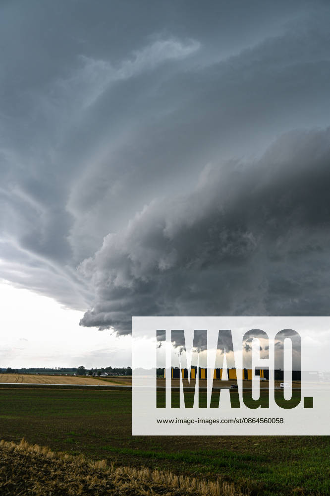 Wetterfeature, Eine mächtige Gewitterzelle zieht am Donnerstagnachmittag über Odelzhausen im Landkreis Dachau. Dunkle Wolken und eine markante Gewitterfront bestimmen den Himmel über der Region. Das Unwetter bringt örtlich Starkregen und kräftige bis stürmische Böen. Ob es durch das aktuell laufende Gewitter zu Schäden gekommen ist, ist derzeit noch nicht bekannt. Odelzhausen Bayern Deutschland Odelzhausen