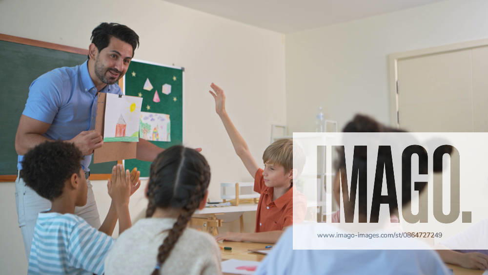 Kunstlehrer, der einer heterogenen Schülergruppe im Klassenzimmer ein farbenfrohes Gemälde vorstellt, Art teacher presenting colorful painting to diverse students in classroom, inspiring creativity and imagination (License=RF) ,model released, Symbolfoto