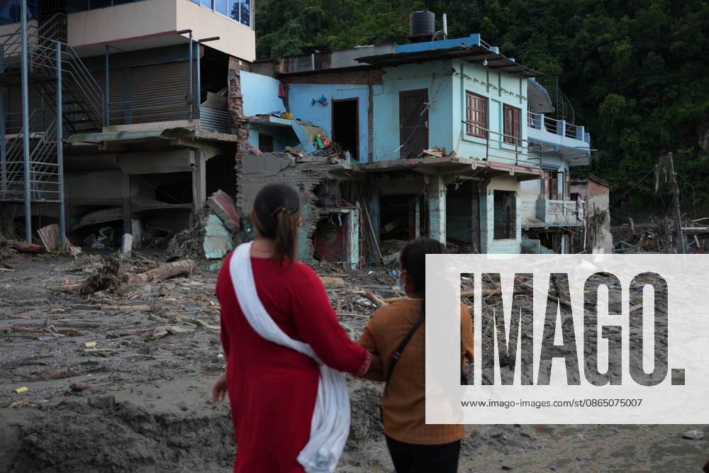 Nepal Flash Flood Leaves Hundreds Missing in Himalayan Border District Women walk past a house damaged by flash floods in Devighat, Nuwakot, Nepal, on August 27, 2026. Kathmandu Nepal