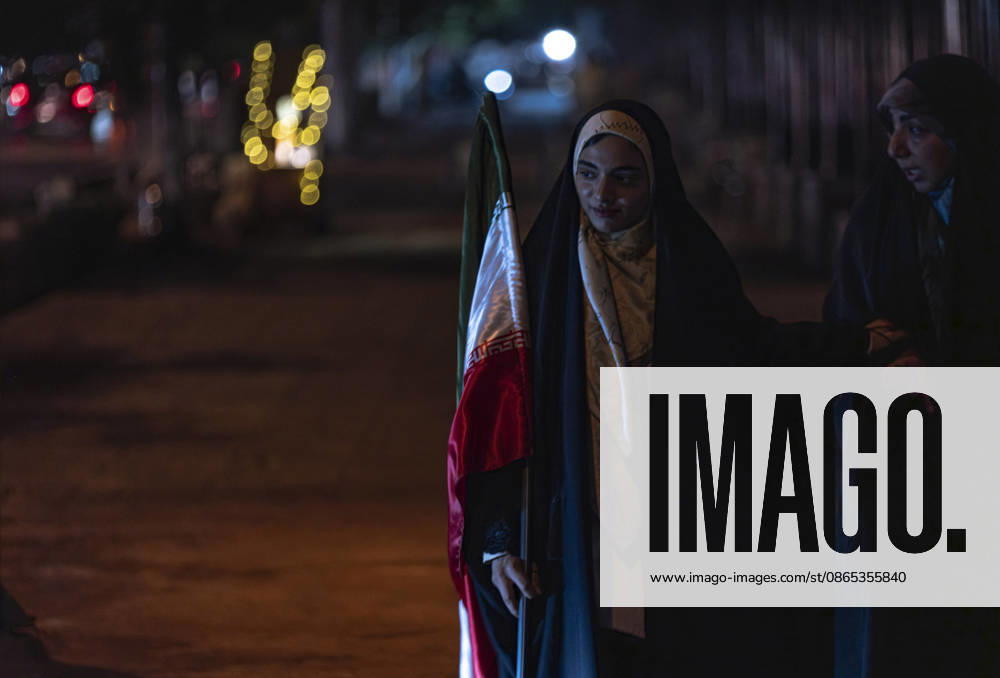 Tehran Nightlife Amid Rising Tensions Between Iran And U.S. A young veiled Iranian woman walks with a relative while carrying a national flag after taking part in a nightly pro-government rally in downtown Tehran, Iran, on August 30, 2026, amid rising tensions between Iran and the United States. U.S. forces struck two Iranian military launchers on Larak Island in the Strait of Hormuz on August 30, in the first reported U.S. attack on Iranian territory since late July. Tehran Tehran Iran