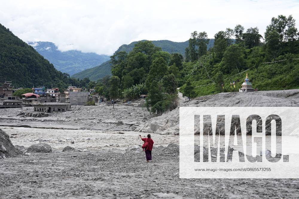 A woman stands with her arms outstretched by a river on a sandbar north in Nuwakot district on September 1, 2026, seven days after deadly mudslides struck the area. Areas of Nepal are still out of the reach of rescue teams, according to the UN, while the death toll from the disaster now exceeds 1,000.