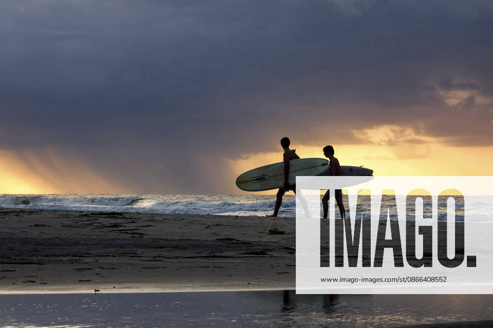 Surfers carry their surfboards along the beach during sunrise as a storm passes over the Atlantic Ocean, September 9, 2026 in Isle of Palms, South Carolina. Isle Of Palms United States - ZUMAe02_ 20260909_zaf_e02_004