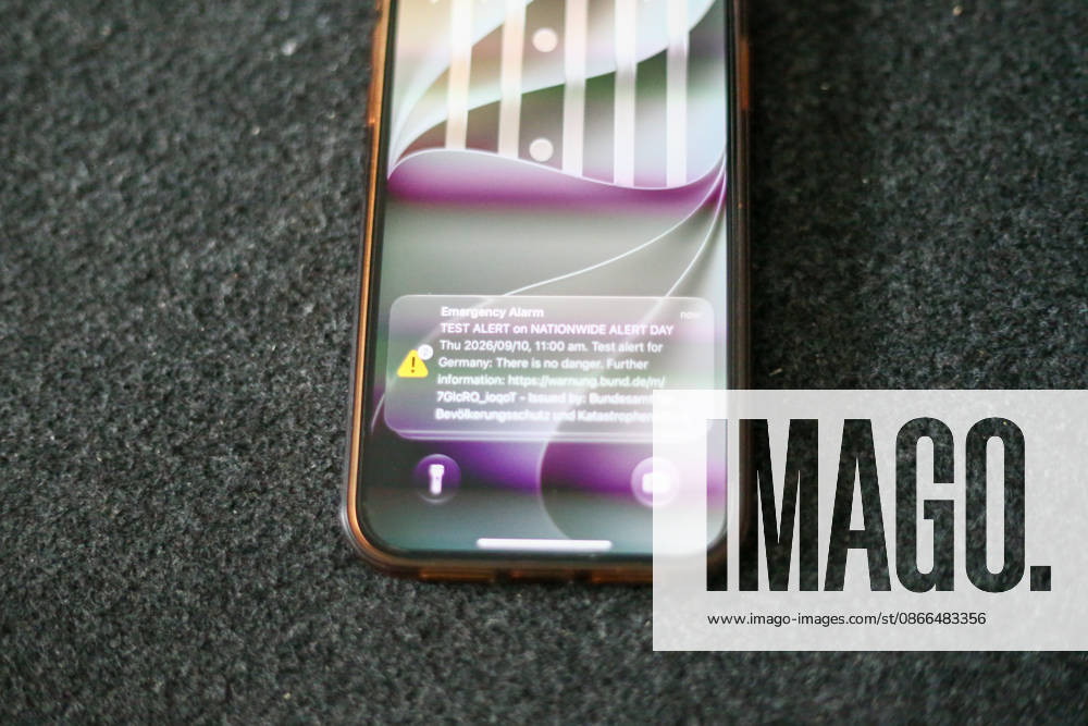 Deutschland, Europa. Smartphone liegt auf einer dunklen Oberfläche und zeigt auf dem Sperrbildschirm eine Testwarnung zum bundesweiten Warntag. Die Cell-Broadcast-Warnmeldung des Bundesamtes für Bevölkerungsschutz und Katastrophenhilfe (BBK) ist auf dem Display sichtbar. Symbolbild zu Notfallwarnsystemen, Bevölkerungsschutz, Krisenvorsorge, digitaler Kommunikation und öffentlicher Sicherheit.