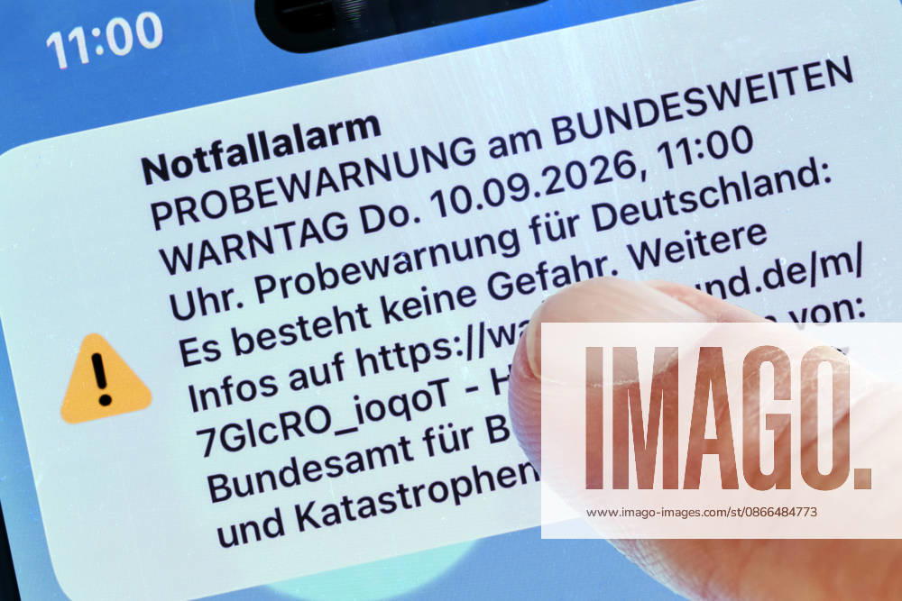 Bundesweiter Warntag, Probealarm um 11 Uhr, Warnmeldung auf dem Smartphone, 10. September 2026 Deutschland, München, 10. September 2026, bundesweiter Warntag, Warnmeldung um 11 Uhr auf einem Smartphone Bildschirm, Katastrophen-Warnsystem, Notfallalarm für den Ernstfall, das Bundesamt für Bevölkerungsschutz und Katastrophenhilfe (BBK) verschickt Push-Nachrichten per Cell Broadcast, Funktionsfähigkeit der Warnsysteme werden überprüft, Smartphone-Nutzer werden als Test über Gefahren und Katastrophen gewarnt, keine Gefahr, Katastrophenschutz, FOTOMONTAGE aus zwei eigenen Bildern, Handy und Finger,