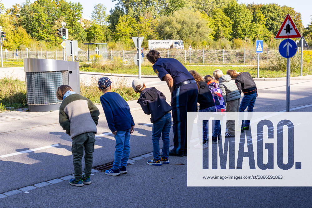 Schulwegtraining mit der Verkehrspolizeiinspektion Augsburg vor dem Schulanfang in Bayern. Kinder üben beim Schulwegtraining in Augsburg mit einer Polizistin das sichere Überqueren einer Straße. Vor dem Queren schauen sie aufmerksam nach links und rechts und trainieren richtiges Verkehrsverhalten