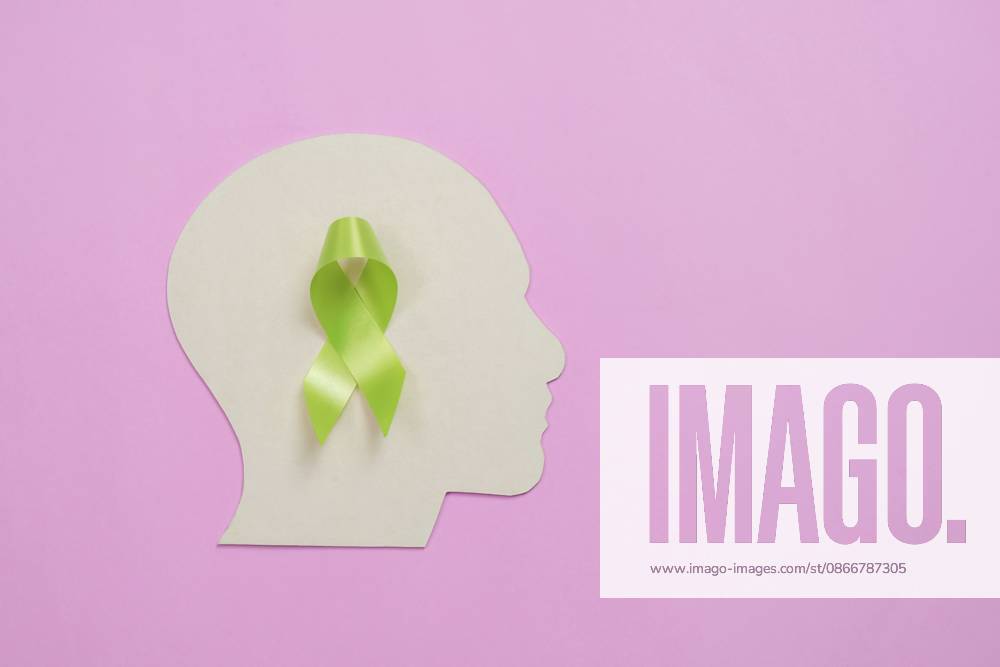 Konzept zur Sensibilisierung und Unterstützung im Bereich der psychischen Gesundheit mit einer grünen Schleife in Form einer Kopfsilhouette auf rosafarbenem Hintergrund Mental health awareness and support concept with a green bow in the shape of a head silhouette on a pink background