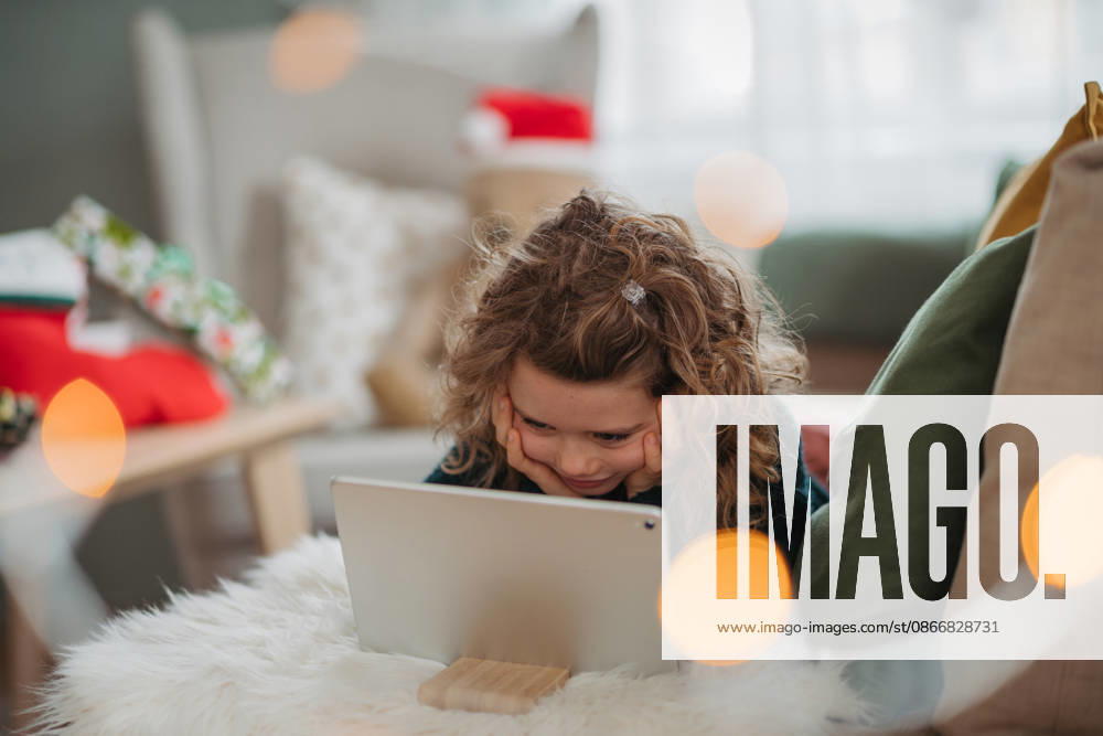Little girl enjoying new tablet received as Christmas present at home. Excited young girl exploring new tablet during Christmas holidays. model released