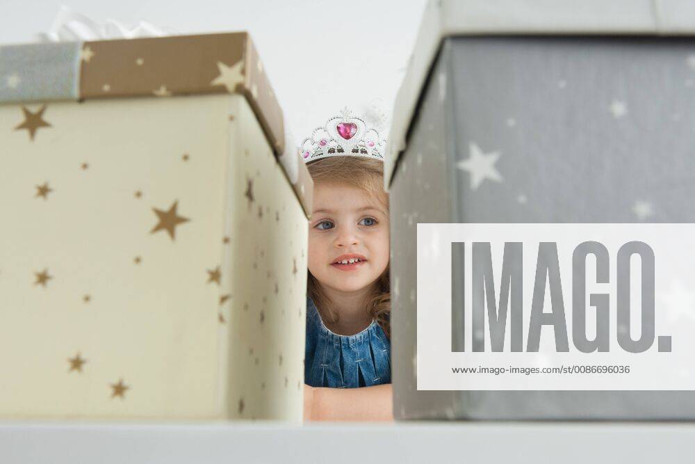 Girl with tiara in front of gift boxes