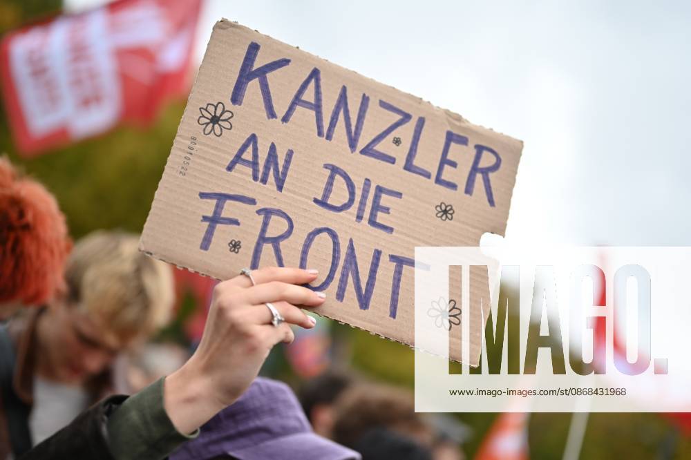 Eine Teilnehmerin haelt am 02.10.2026 einen Pappkarton mit dem Satz Kanzler an die Front waehrend einer Kundgebung vor dem Brandenburger Tor unter dem Motto Unzwingbar - Kein Bock auf Krieg und Wehrpflicht . Zu den Veranstaltern der Demonstration zaehlen unter anderem Attac, die Deutsche Friedensgesellschaft und der Internationale Jugendverband. In einem vorab verbreiteten Aufruf stellten sich die Organisationen etwa gegen eine Wiedereinfuehrung der Wehrpflicht und die Anwerbung Jugendlicher unter 18 Jahren fuer die Bundeswehr. Das Buendnis forderte zudem mehr Geld fuer Bildung, Gesundheit und Soziales statt fuer Krieg. Angekuendigt waren Redebeitraege unter anderem von Gewerkschaftern, Schueler- und Studentengruppen und der Schulstreikb