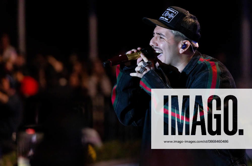 Vocalist PEDRO TOVAR of the American regional Mexican group ESLABON ARMADO sings into a golden microphone during a live concert performance at Teatro de la Ciudad in Parque Tangamanga 1 in San Luis Potosi, Mexico. He wears a branded cap and a black jacket with red and green stripes. San Luis Potosi Mexico - ZUMAm311 20261002_zip_m311_002