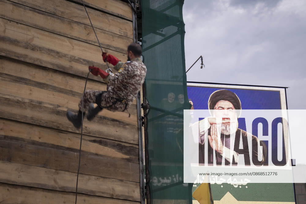 Opening Ceremony Of Second City-Square Military Training Camp An armed Iranian Army serviceman stands next to a portrait of the late Hezbollah Secretary-General Hassan Nasrallah during the opening ceremony of the second city-square military training camp for self-sacrificing forces in downtown Tehran, Iran, on October 3, 2026. The camp was established by the Basij paramilitary force, with personnel from the Islamic Republic of Iran Army responsible for training the volunteers. Tehran Tehran Iran