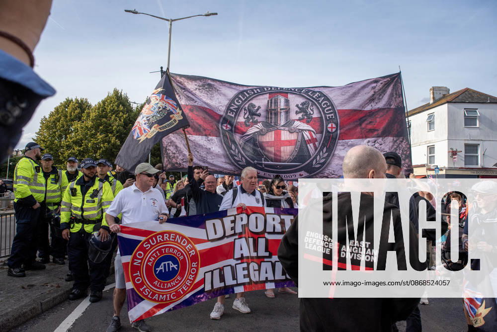 Far-right protesters march with banner and flags to the harbour during a demonstration in Dover. Supporters of the English Defence League (EDL) gathered in Dover, UK to march through the town all the way to the harbour. English Defence League is an extreme far-right and Islamophobic organisation. It was founded by Tommy Robinson (pseudonym of Steven Yaxley-Lennon) in 2009. Dover United Kingdom - ZUMAs197 20261003_aaa_s197_264