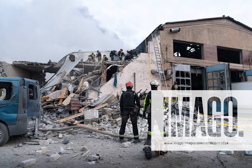 Local rescue workers, firefighters and Red Cross volunteers clear rubble following a Russian aerial attack on a bus repair warehouse which killed two people in Kharkiv, Ukraine. Emergency crews search through the heavily damaged building and collapsed sections of the warehouse for survivors and the remains of those killed in the attack. Kharkiv Ukraine - ZUMAm350 20261005_zip_m350_014