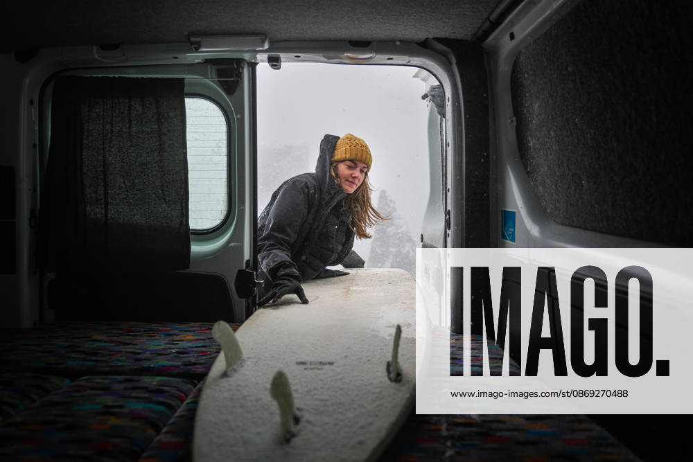 Young woman loading her snowy surfboard into a camper van Keflavík, Reykjanesbær, Iceland CR_ALEG261005-2129018-01 ,model released, Symbolfoto ,property released