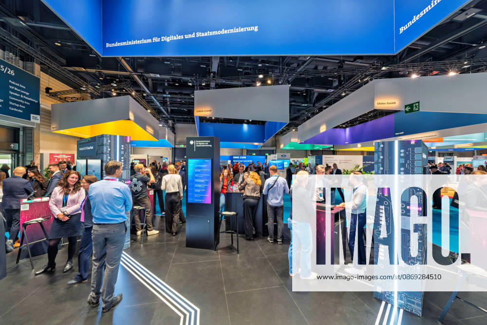 Berlin, 13.10.2026: Dichtes Gedränge am Stand des Bundesministeriums für Digitales und Staatsmodernisierung auf der Smart Country Convention, mit beleuchteten Infostelen im Platinen-Design; im Hintergrund die Stände von IONOS Cloud und Ubitec. Das 2025 gegründete Ministerium unter Karsten Wildberger soll die Digitalisierung des Staates bündeln. Die Smart Country Convention (SCCON) ist die Kongressmesse für die Digitalisierung des öffentlichen Sektors und wird vom Digitalverband Bitkom gemeinsam mit der Messe Berlin veranstaltet. Vom 13. bis 15. Oktober 2026 treffen sich auf dem Berliner Messegelände Vertreter aus Bund, Ländern und Kommunen mit Unternehmen der Digitalwirtschaft, um über digitale Verwaltung, Smart City und digitale