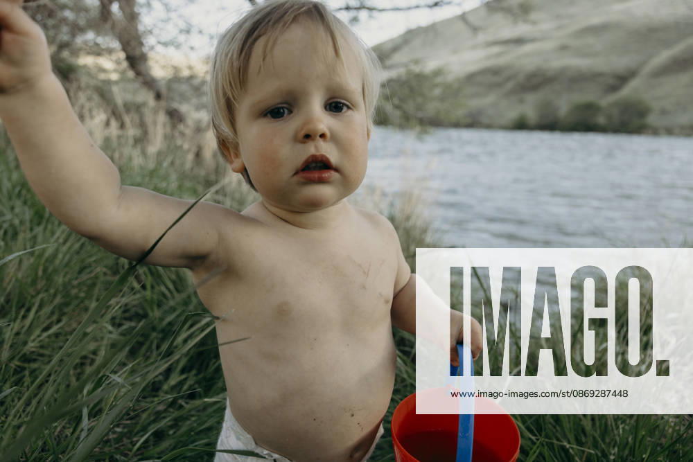 Cute toddler boy holding a red bucket by a river The Dalles, Oregon, United States CR_XICZ261001B9-2131791-01 ,model released, Symbolfoto ,property released