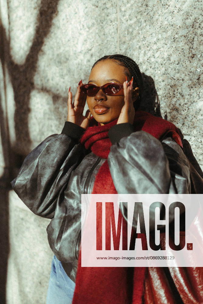 Stylish young woman adjusts her red sunglasses outdoors Cape Town, Western Cape, South Africa CR_YNJN261001-2126858-01 ,model released, Symbolfoto ,property released