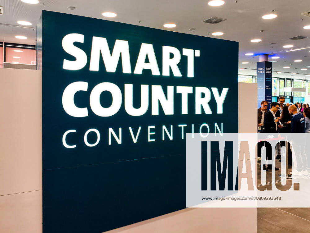 Grosses beleuchtetes Logo der Smart Country Convention (SCCON) im Eingangsbereich der Messe Berlin. Besucher und Fachpublikum stehen am Einlass der Kongressmesse. Smart Country Convention, SCCON 2026, Berlin, Messe, Digitalisierung, Digitalpolitik, Smart City, Smart Country, öffentliche Verwaltung, E-Government, digitale Transformation, IT, Technologie, Wirtschaft, Innovation, Kongress, Fachmesse, Besucher, Registrierung, Eingang, Veranstaltungslogo.