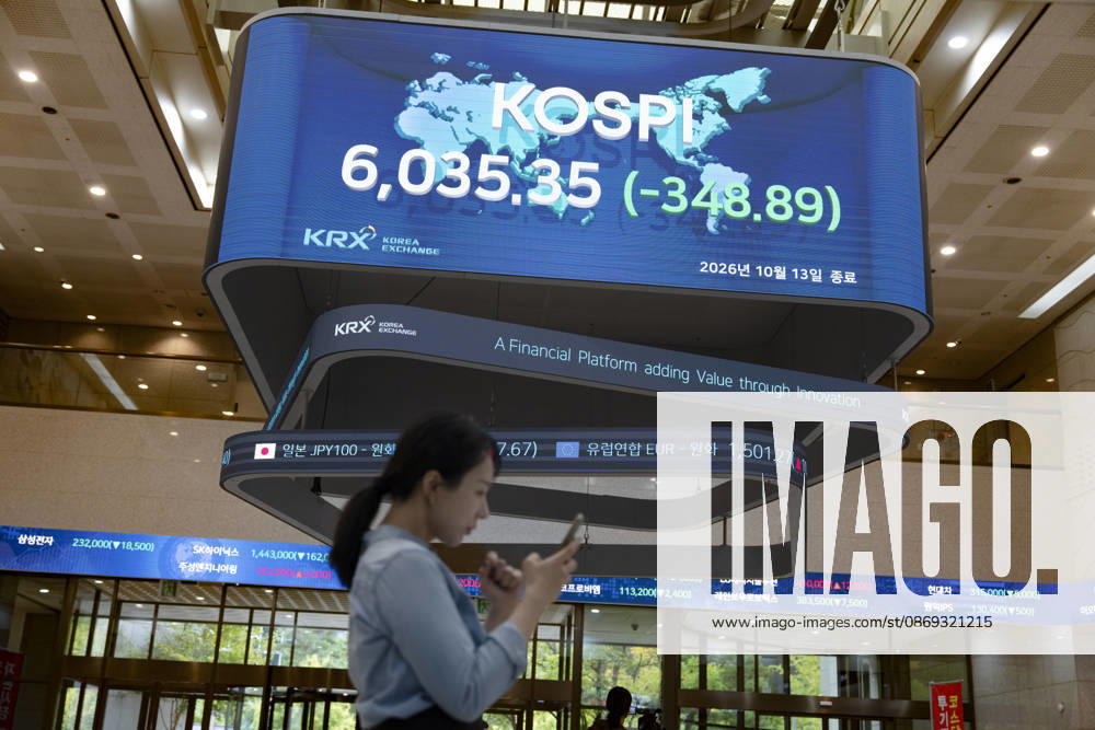 South Korea Stocks Plunge As KOSPI Drops Sharply At KRX In Seoul A Korea Exchange (KRX) employee looks at her smartphone while walking past a display board showing the closing KOSPI index at 6,035.35 (-348.89) in Yeouido, Seoul, South Korea, on October 13, 2026. Seoul Seoul South Korea