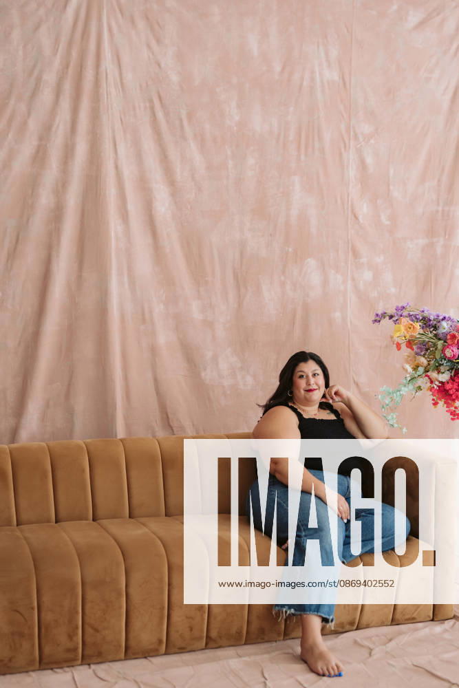 Joyful Woman Laughing on a Vintage Sofa Surrounded by Colorful Flowers Cincinnati, Ohio, United States CR_QUNR260930-2131835-01 ,model released, Symbolfoto ,property released