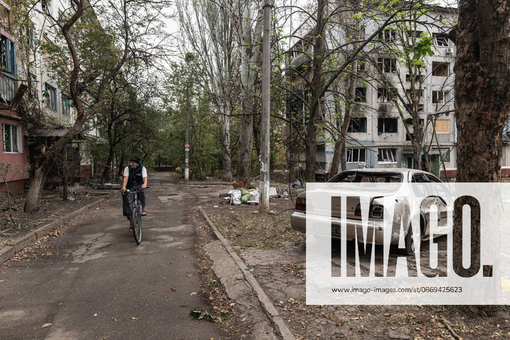 Russian air strike hits residential building in Kramatorsk KRAMATORSK, UKRAINE - OCTOBER 14: A woman on a bicycle rides past a car damaged by Russian bombing in Kramatorsk, Ukraine, on October 14, 2026. Diego Herrera Carcedo Anadolu Kramatorsk Ukraine. Editorial use only. Please get in touch for any other usage.