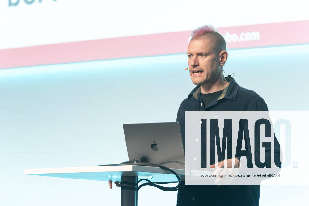 Berlin, 16.10.2026: Auf der NeulandPro Connect 2026 spricht der Publizist und Digital-Vordenker Sascha Lobo am Rednerpult, hinter ihm die Leinwand mit seiner Webadresse saschalobo.com. Die zweitägige KI-Konferenz NeulandPro Connect 2026 findet am 16. und 17. Oktober im Westhafen Event & Convention Center (WECC) in Moabit statt, einem historischen Speichergebäude am Berliner Westhafen. Veranstalter ist NeulandPro, eine Bildungs- und Medienmarke rund um Künstliche Intelligenz. Mit Vorträgen, Workshops und Hackathons richtet sich die Konferenz vor allem an kleine und mittelständische Unternehmen, Gründer und Führungskräfte, die KI praktisch einsetzen wollen; erwartet werden bis zu 1.000 Gäste. NeulandPro Connect 2026 - KI-Konferenz in