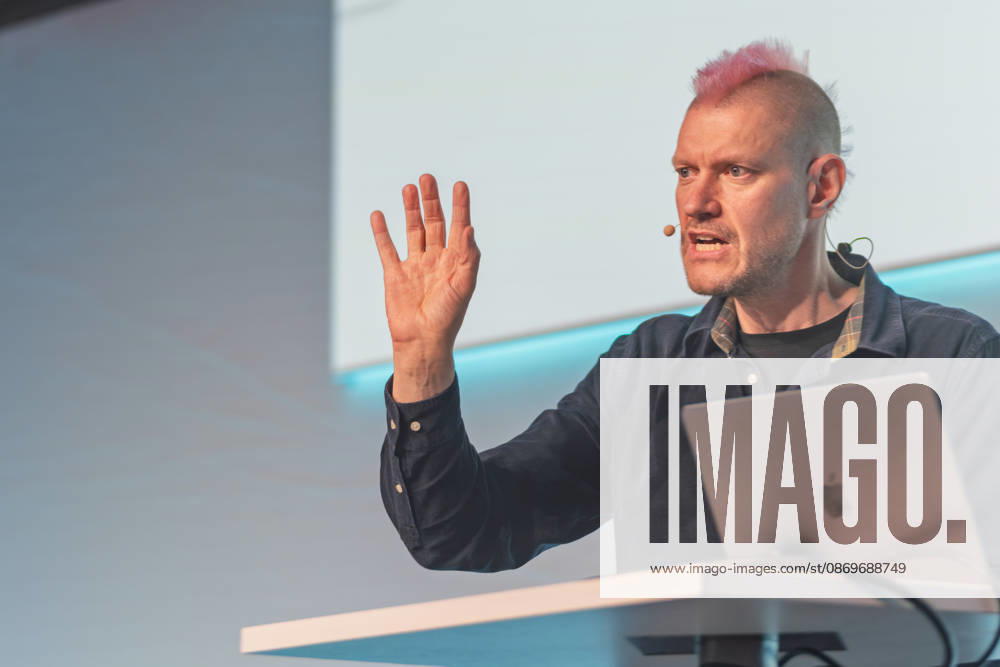 Berlin, 16.10.2026: Auf der NeulandPro Connect 2026 hebt der Publizist und Digital-Vordenker Sascha Lobo während seines Vortrags die Hand. Die zweitägige KI-Konferenz NeulandPro Connect 2026 findet am 16. und 17. Oktober im Westhafen Event & Convention Center (WECC) in Moabit statt, einem historischen Speichergebäude am Berliner Westhafen. Veranstalter ist NeulandPro, eine Bildungs- und Medienmarke rund um Künstliche Intelligenz. Mit Vorträgen, Workshops und Hackathons richtet sich die Konferenz vor allem an kleine und mittelständische Unternehmen, Gründer und Führungskräfte, die KI praktisch einsetzen wollen; erwartet werden bis zu 1.000 Gäste. NeulandPro Connect 2026 - KI-Konferenz in Berlin