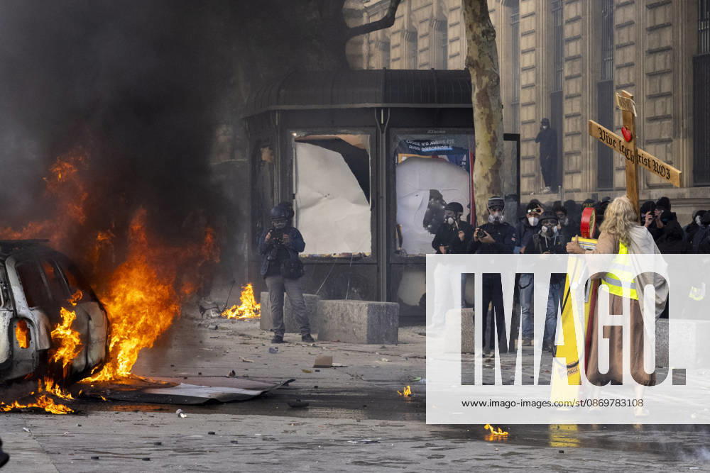 A man dressed as Jesus, wearing a yellow vest and carrying a wooden cross, stands near a burning car during demonstrations in Paris, France, on October 17, 2026. Students and Yellow Vest protesters demonstrated over rising living costs and conditions in education. Paris France - ZUMAl165 20261017_zip_l165_022
