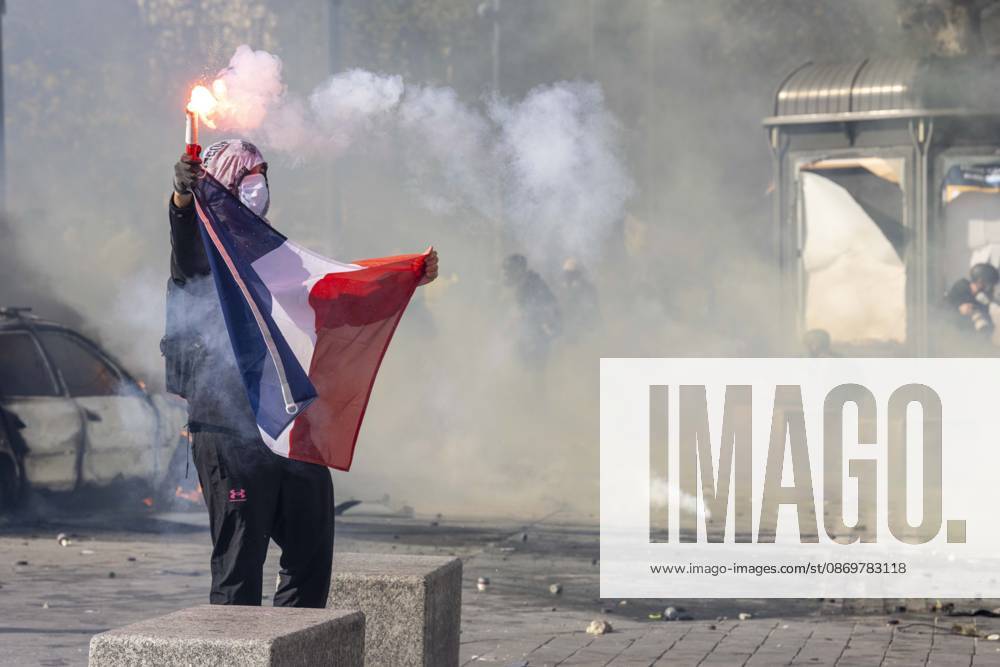A masked demonstrator raises a lit flare while holding a French flag amid smoke and tear gas during protests in Paris, France, on October 17, 2026. Students and Yellow Vest protesters demonstrated over rising living costs and conditions in education. Paris France - ZUMAl165 20261017_zip_l165_027